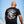 Man wearing a black t-shirt with 'Strength Beyond Pain' design against a blue sky.